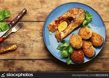 Baked fish cutlets and tasty fish steak on rural wooden surface. Delicious fried fish cutlet