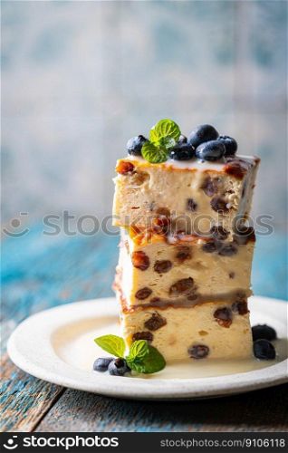 Baked homemade cottage cheese casserole or pudding with raisins serving with blueberry and sour cream on blue background. Close-up.. Cottage cheese casserole