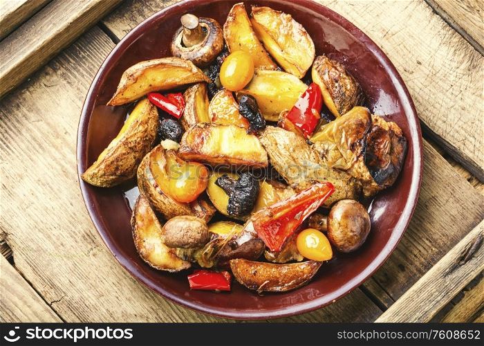 Baked homemade potato with champignon mushrooms. Fried potatoes on a wooden vintage background.. Fried potatoes with mushrooms