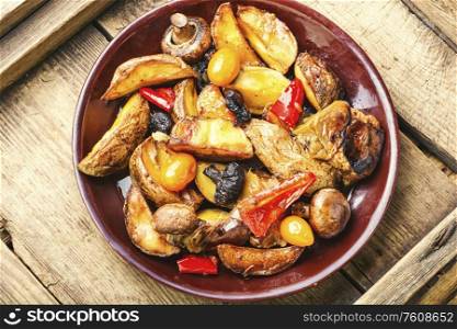 Baked homemade potato with champignon mushrooms. Fried potatoes on a wooden vintage background.. Fried potatoes with mushrooms