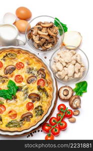 Baked homemade quiche pie with tomato, chcken and mushrooms in ceramic baking form, eggs and cream isolated on white background. Baked homemade quiche pie in ceramic baking form, eggs and cream