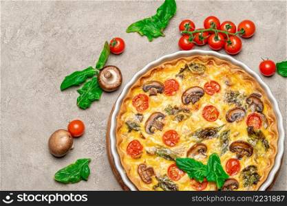 Baked homemade quiche pie with tomato, chcken and mushrooms in ceramic baking form on concrete background. Baked homemade quiche pie in ceramic baking form on concrete background