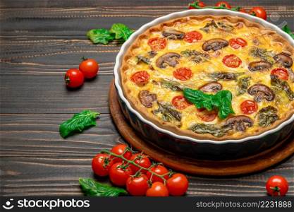 Baked homemade quiche pie with tomato, chcken and mushrooms in ceramic baking form on concrete background. Baked homemade quiche pie in ceramic baking form on concrete background