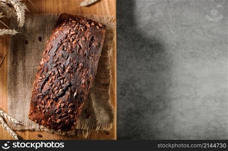 Baked loaf of bread on a napkin, on a cutting board, top view with copy space for advertising or recipe. Naturally fermented bread, healthy food. Layout on a gray table