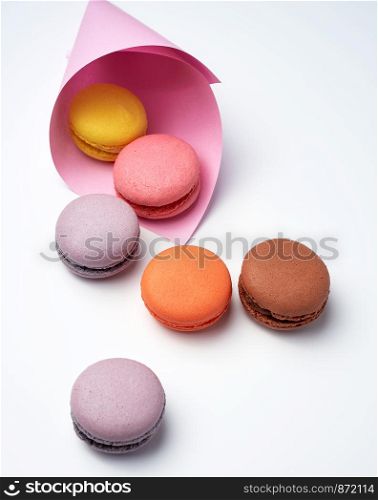 baked macarons in a pink paper bag on a white background, close up