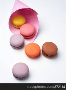 baked macarons in a pink paper bag on a white background, close up
