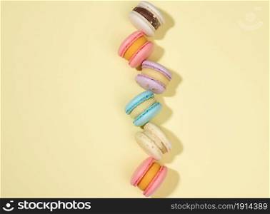 baked macarons with different flavors on a beige background, top view