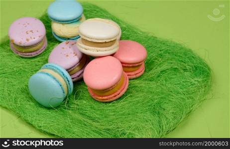 baked macarons with different flavors on a green background, top view