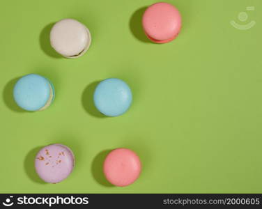 baked macarons with different flavors on a green background, top view