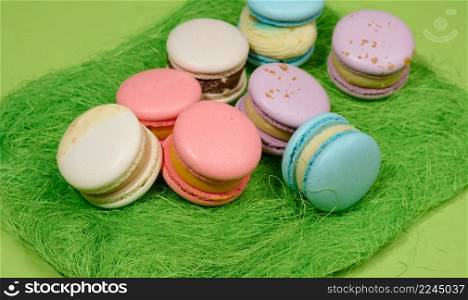 baked macarons with different flavors on a green background, top view