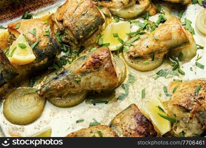 Baked mackerel with onions and herbs. Sliced baked mackerel on an onion pillow