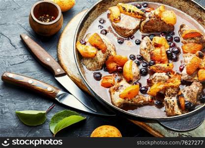 Baked meat in red wine with apricot and blackcurrant.Stewed pork in iron cast pan. Stew meat with apricot.