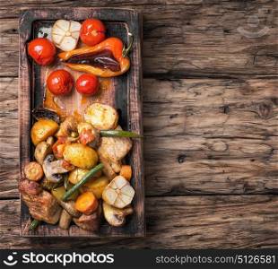 Baked meat with vegetables. Meat baked with potatoes and mushrooms on vintage wooden background