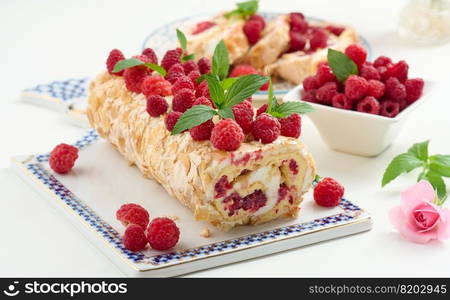 Baked meringue roll with cream and fresh red raspberry on a white board, delicious dessert 