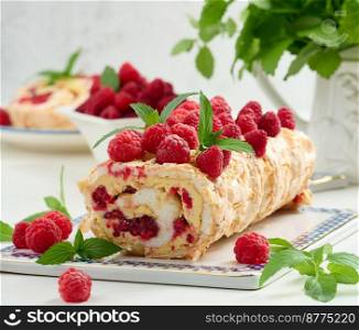 Baked meringue roll with cream and fresh red raspberry, white background	