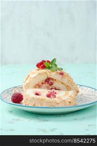 Baked meringue roll with red berries on a round plate, white background