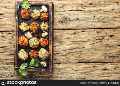 Baked mushrooms stuffed with cheese on cutting board.Italian food.Party snack. Mushrooms stuffed with vegetables