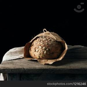 baked oval bread made from rye flour with pumpkin seeds, black background