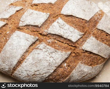 baked oval rye flour bread in a metal baking sheet on the table, top view