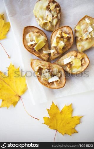 Baked pears with brie cheese and nuts against the background of autumn yellow leaves.. Baked pears with brie cheese and nuts against the background of autumn yellow leaves