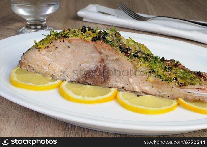 Baked piece of carp with lemon dill sauce on a plate