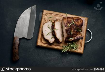baked piece of pork meat in spices on a wooden board, cut into pieces. Eye of round roast steak