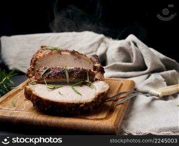 baked piece of pork meat in spices on a wooden board, cut into pieces. Eye of round roast steak