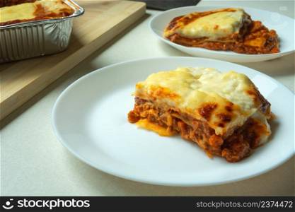 Baked pieces of lasagne on a white round plate