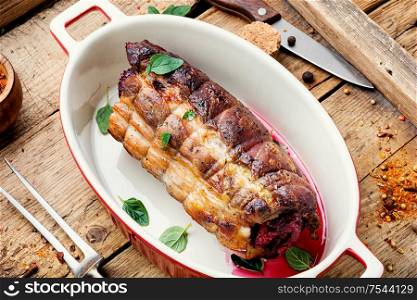 Baked pork meat stuffed cherries.Baked pork on a wooden retro tray. Baked meat on a wooden background