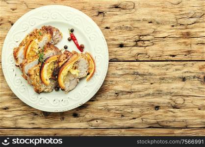 Baked pork meat stuffed with orange and seasonings.Grilled pork with orange fruit. Baked meat in oranges