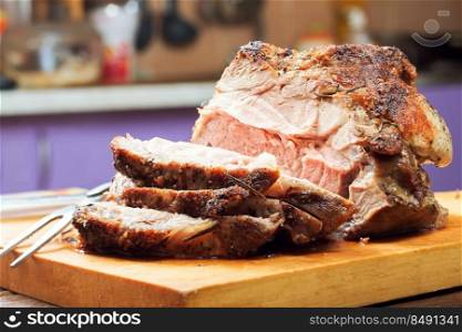Baked pork meat with spices sliced on a cutting board on the kitchen background. baked pork meat
