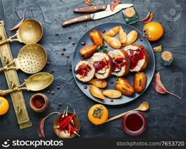 Baked pork roll with autumn persimmon.Meat stuffed with fruits.Autumn food. Meatloaf with persimmon on plate