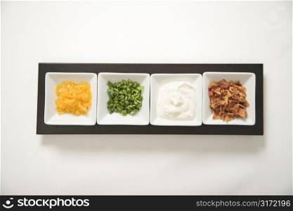 Baked potato side dishes filled with cheese, scallion onions, sour cream, and bacon.