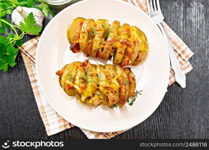 Baked potatoes layered with smoked bacon and cheese in a plate on a napkin on wooden board background from above