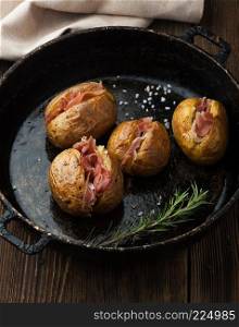 Baked potatoes with prosciutto and cheese in a pan
