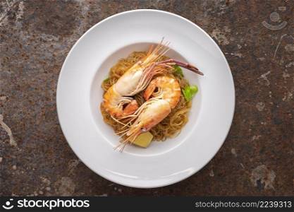 baked prawns with vermicelli, casseroled shrimps with glass noodles in white simply ceramic plate on rusty texture background, top view, flat lay, river prawn