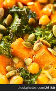 Baked pumpkin, kale and chickpea casserole with pumpkin seeds on top, photographed with natural light (Selective Focus, Focus one third into the image)