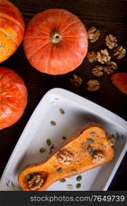 baked pumpkin with walnuts and seeds, coconut milk served at wooden brown table with ripe orange pumkins. flat lay. healthy life concept