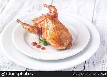 Baked quail wrapped in bacon on the plate