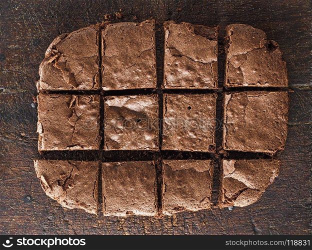 baked rectangular chocolate brownie pie is cut into squares, a wooden brown table