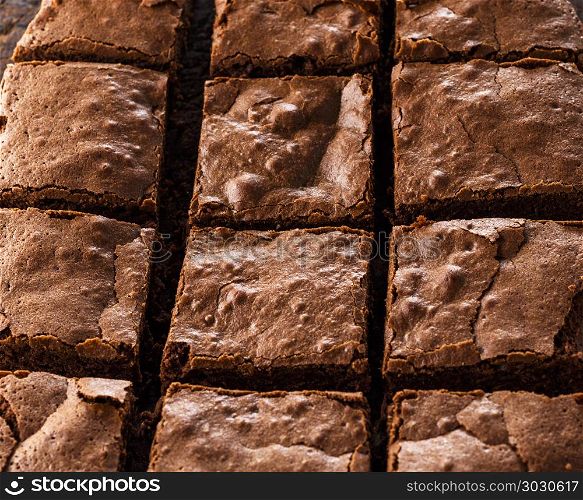 baked rectangular chocolate brownie pie is cut into squares, a wooden table, a full frame. baked rectangular chocolate brownie pie is cut into squares
