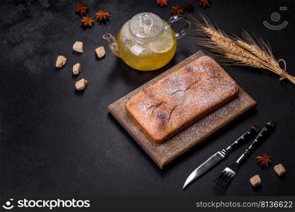 Baked rectangular cupcake with raisins and chocolate on a dark concrete background. Homemade delicious pastries. Baked rectangular cupcake with raisins and chocolate on a dark concrete background