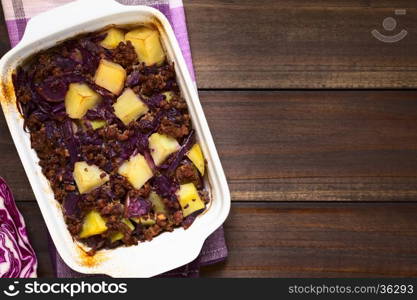 Baked red cabbage, apple, mincemeat and potato casserole in dish, photographed overhead on dark wood with natural light (Selective Focus, Focus on the top of the dish)