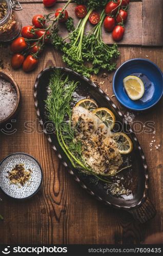 Baked roasted fish fillet in fish baking form with dill and lemon slices on wooden background, top view. Home cuisine concept. Seafood, low carb and dieting nutrition