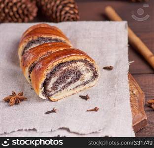 baked roll with poppy seeds on a wooden board, close up
