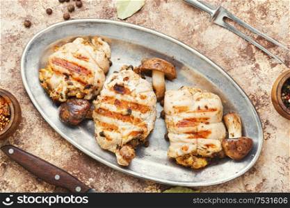Baked rolled chicken meat with mushrooms on a metal stylish dish. Chicken roll with mushrooms