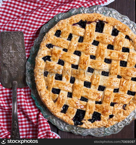 baked round black currant cake on wooden background, top view