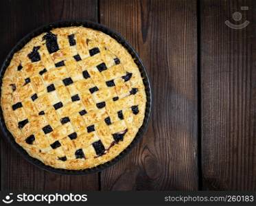 baked round black currant cake on wooden background, top view, copy space