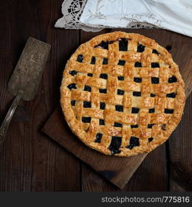 baked round black currant cake , top view, wooden brown background