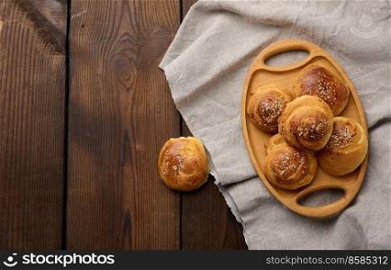 Baked round buns on a wooden table, top view